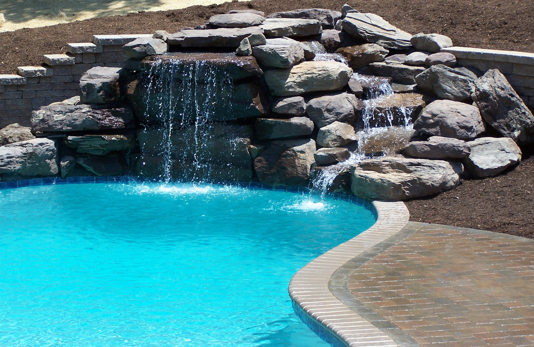 swimming pool with stone waterfall Land Tech Group