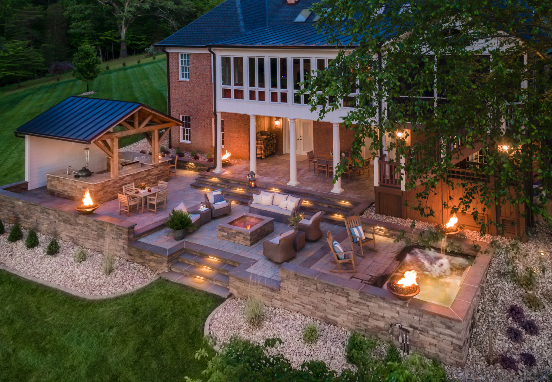 patio with retaining walls, spa, fire bowls, fire pit by Land Tech Group